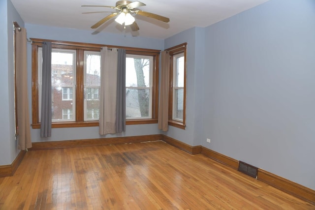 unfurnished room with a ceiling fan, light wood-style flooring, baseboards, and visible vents