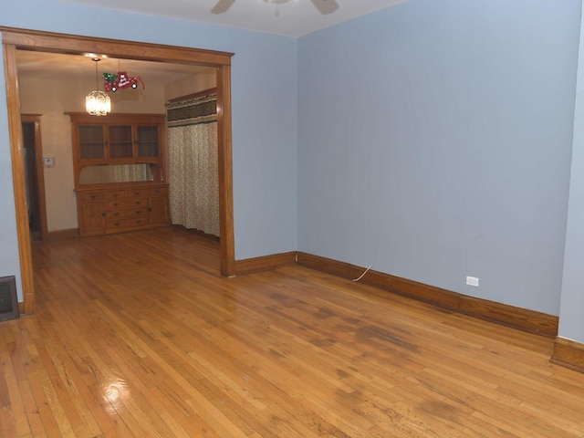 empty room featuring baseboards, light wood-style floors, and a ceiling fan