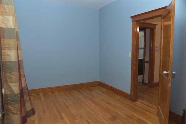 unfurnished room with baseboards and hardwood / wood-style flooring