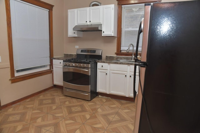 kitchen with stainless steel appliances, under cabinet range hood, a sink, dark countertops, and white cabinets