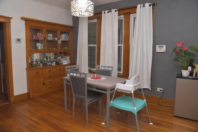 dining space with baseboards, a notable chandelier, and wood finished floors