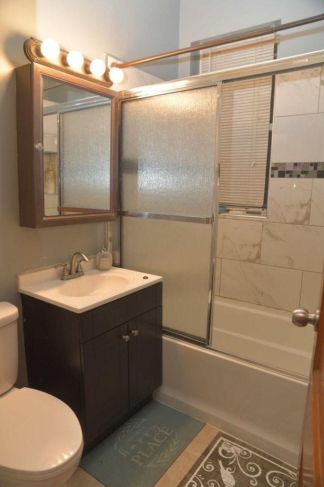 full bath featuring tile patterned floors, bath / shower combo with glass door, toilet, and vanity