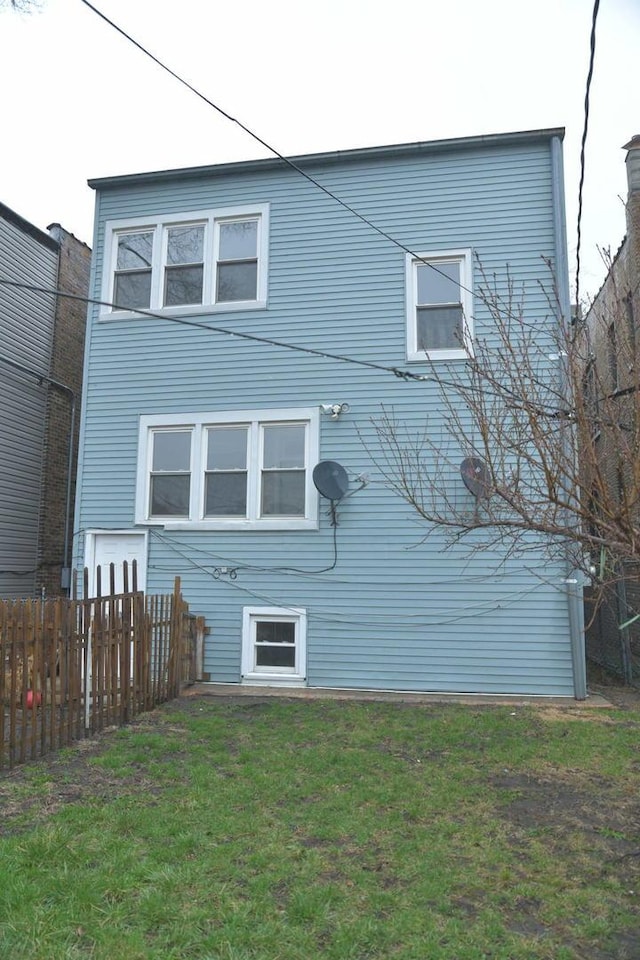 back of property with fence and a yard