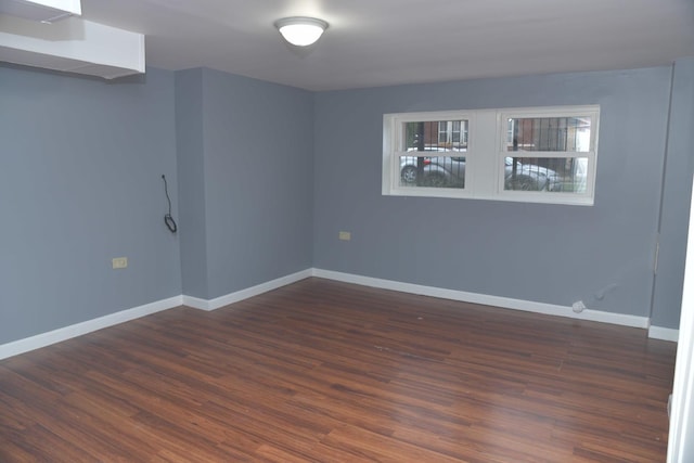spare room with dark wood-style flooring and baseboards