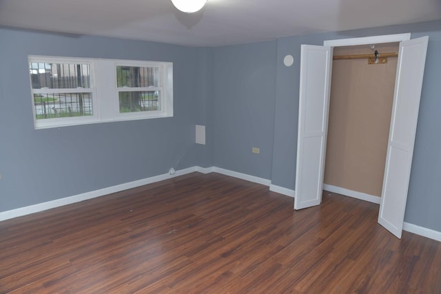 unfurnished bedroom featuring dark wood-style floors, a closet, and baseboards