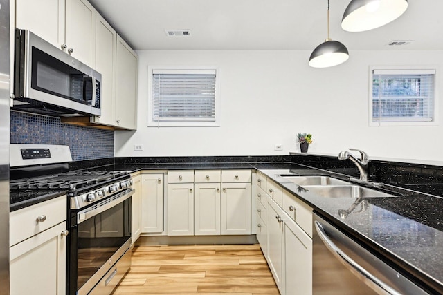 4310 N Richmond St Unit 1, Chicago, IL 60618 - kitchen featuring stainless steel appliances, a sink, light wood-type flooring, dark stone countertops, and backsplash