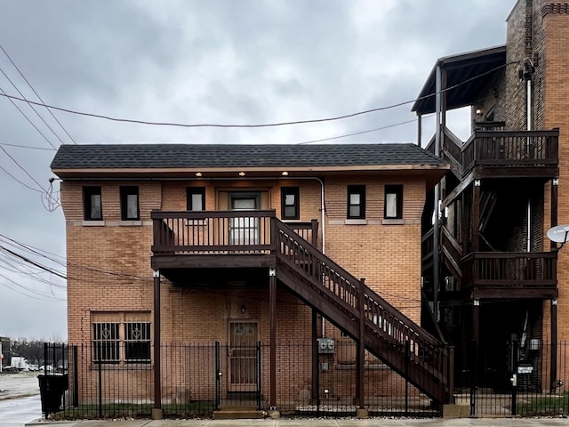view of front facade featuring brick siding and roof with shingles