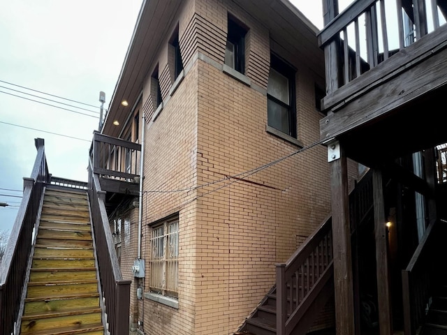 view of side of home featuring brick siding and stairway