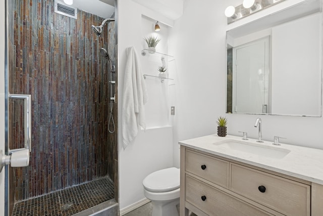 full bathroom featuring visible vents, vanity, a tile shower, and toilet