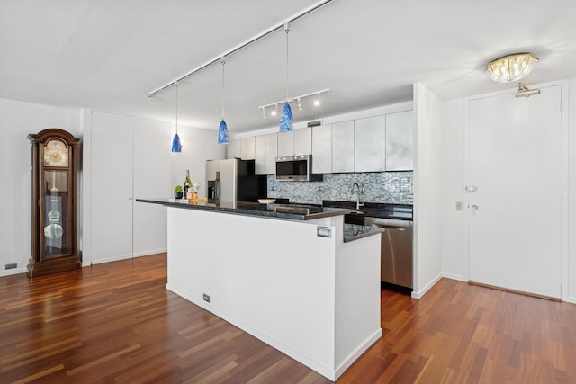 kitchen featuring stainless steel appliances, a center island, dark wood-style floors, tasteful backsplash, and rail lighting