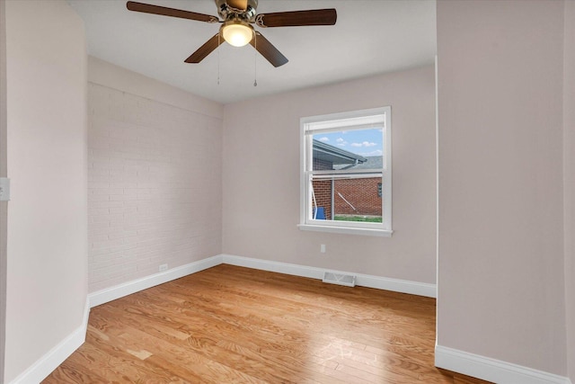 empty room with baseboards, visible vents, ceiling fan, and light wood-type flooring