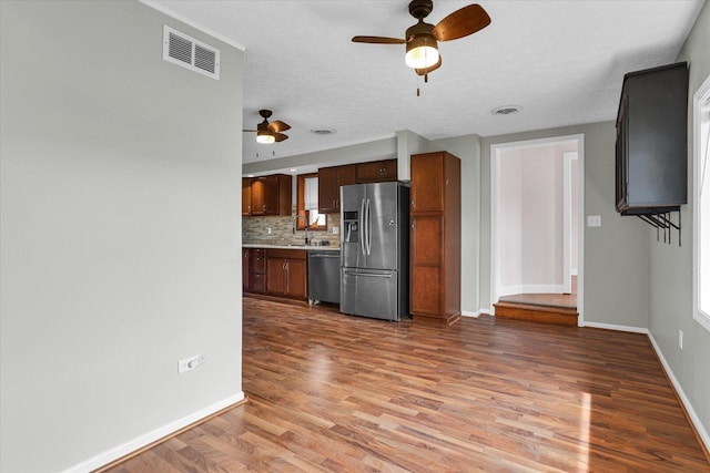 kitchen featuring backsplash, a ceiling fan, wood finished floors, appliances with stainless steel finishes, and visible vents