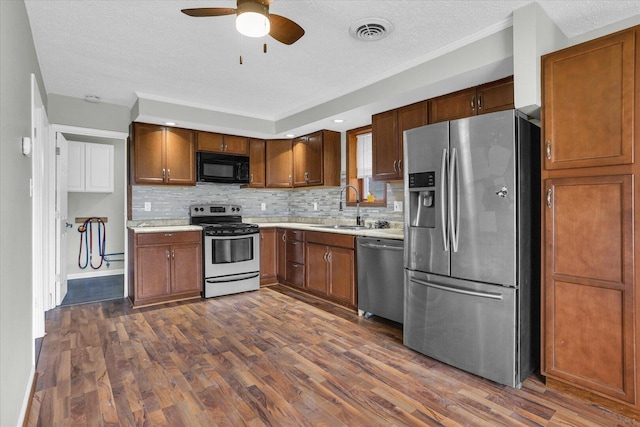 kitchen with light countertops, dark wood finished floors, a sink, ceiling fan, and appliances with stainless steel finishes