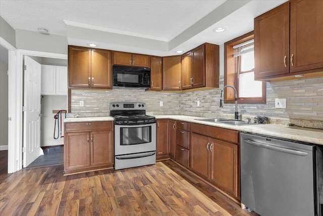 kitchen with dark wood-style flooring, light countertops, appliances with stainless steel finishes, a sink, and brown cabinetry