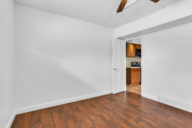 spare room featuring dark wood-type flooring, baseboards, and visible vents
