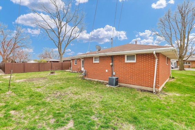 rear view of property with brick siding, fence, an outdoor fire pit, and a yard