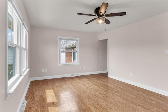 spare room with wood finished floors, baseboards, ceiling fan, and visible vents