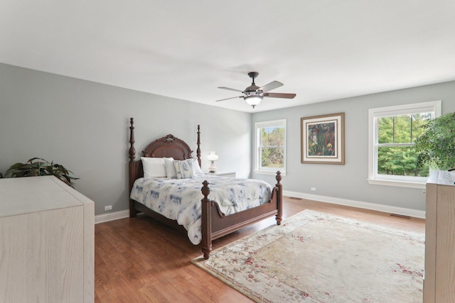 bedroom featuring baseboards, visible vents, wood finished floors, and ceiling fan