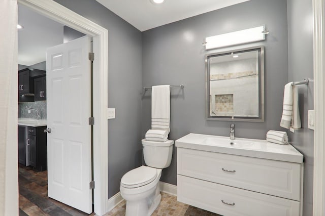 bathroom featuring toilet, vanity, and baseboards