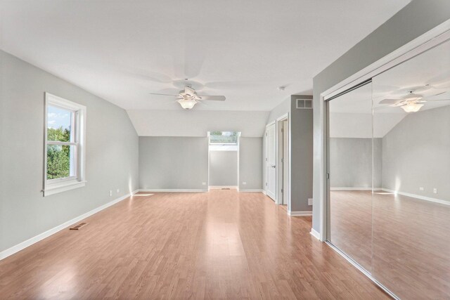 unfurnished bedroom featuring baseboards, visible vents, lofted ceiling, and light wood-type flooring