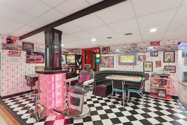 game room featuring a bar, tile patterned floors, a drop ceiling, and visible vents