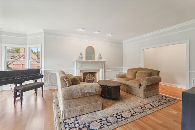 living area featuring a wainscoted wall, a fireplace, wood finished floors, and ornamental molding