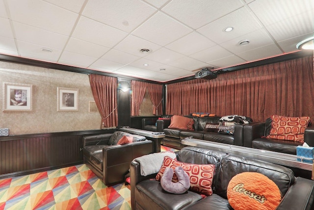 cinema featuring a wainscoted wall, visible vents, and a drop ceiling