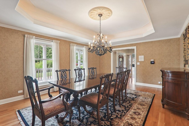 dining room with baseboards, a tray ceiling, a notable chandelier, and light wood finished floors