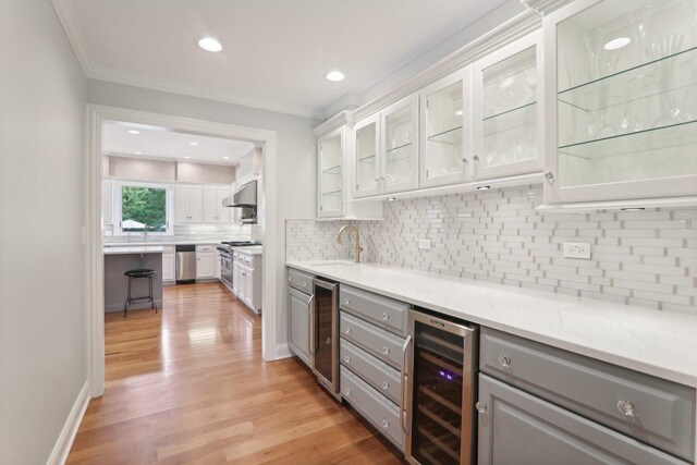 kitchen featuring gray cabinets, under cabinet range hood, wine cooler, and light wood-style flooring