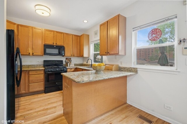 4134 S Ellis Ave, Chicago, IL 60653 - kitchen with black appliances, a sink, a peninsula, light wood finished floors, and light stone counters