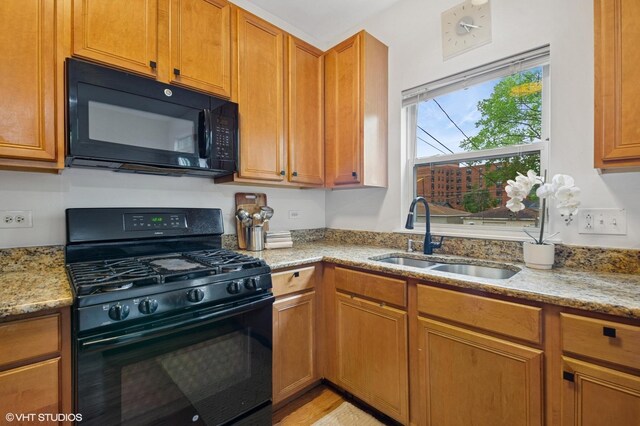 4134 S Ellis Ave, Chicago, IL 60653 - kitchen with black appliances, a sink, light stone counters, and brown cabinets