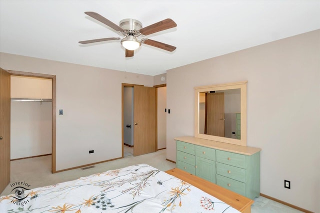 bedroom with a spacious closet, baseboards, light colored carpet, and ceiling fan