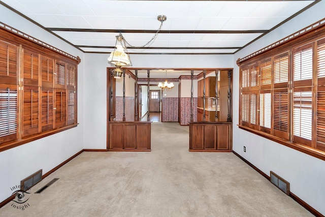 spare room featuring a wealth of natural light, visible vents, an inviting chandelier, and light colored carpet