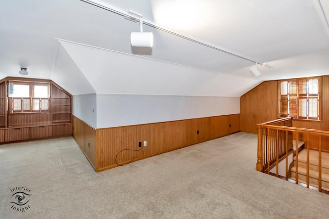 additional living space featuring carpet, a wainscoted wall, wood walls, and lofted ceiling