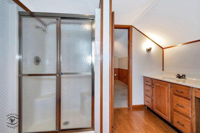 bathroom with a shower stall, wallpapered walls, and wood finished floors