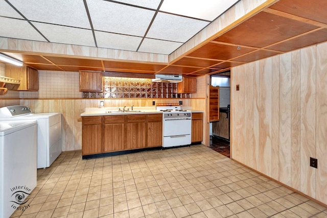 kitchen featuring light countertops, independent washer and dryer, wood walls, ventilation hood, and white gas range oven