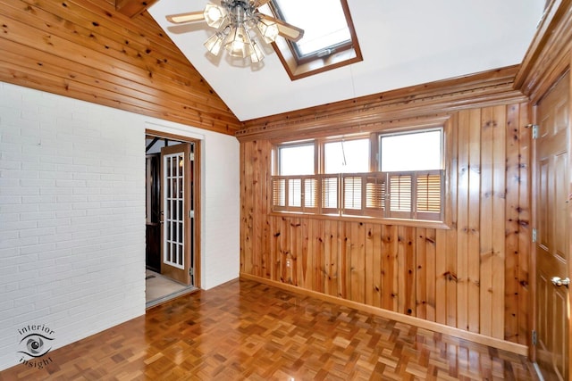 unfurnished room with a skylight, wood walls, and ceiling fan