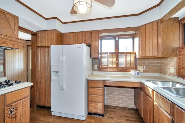 kitchen featuring crown molding, light countertops, backsplash, a sink, and white appliances