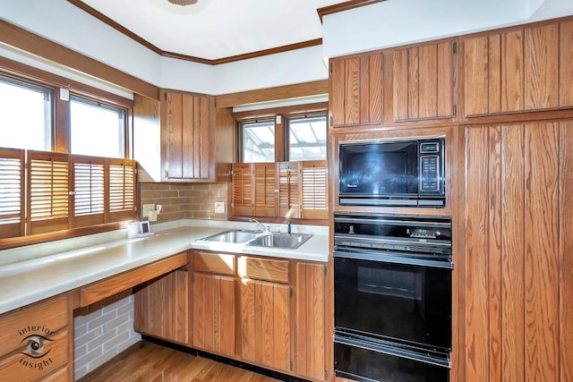 kitchen featuring light countertops, a warming drawer, ornamental molding, a sink, and black appliances