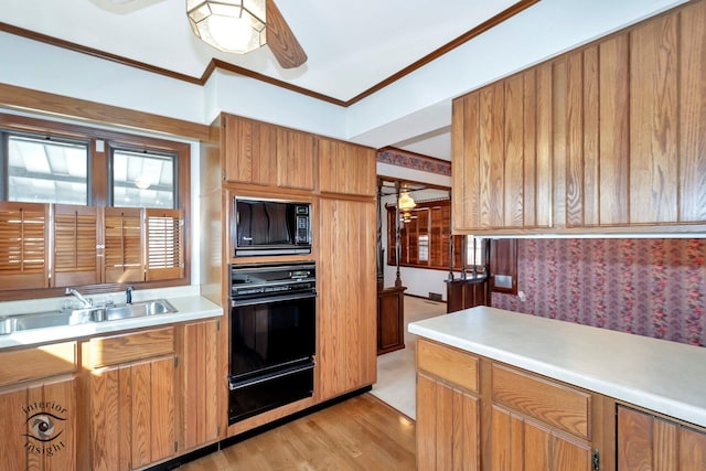 kitchen with light countertops, a sink, a warming drawer, and black appliances