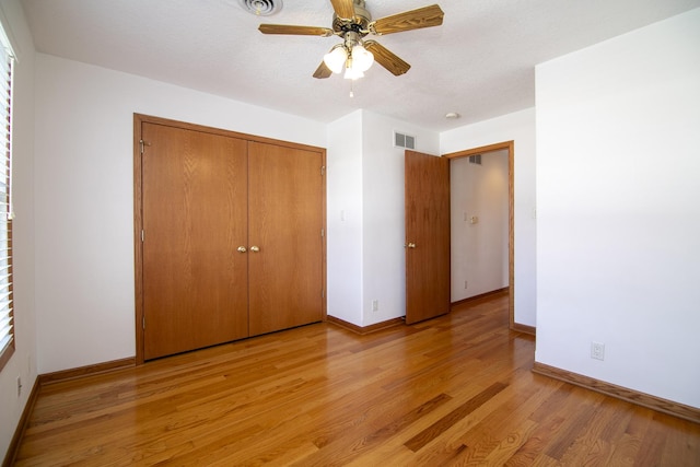 unfurnished bedroom featuring a closet, visible vents, baseboards, a ceiling fan, and light wood-style floors