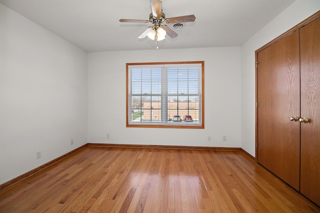 unfurnished bedroom featuring a ceiling fan, baseboards, a closet, and light wood-type flooring