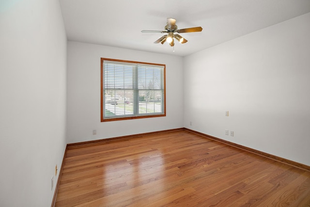 empty room featuring light wood finished floors, baseboards, and a ceiling fan