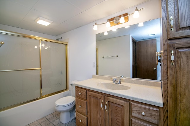 bathroom with toilet, shower / bath combination with glass door, tile patterned flooring, and vanity