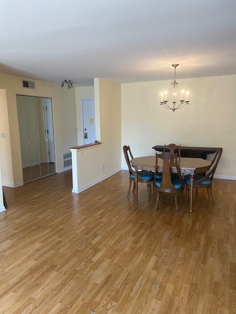 4901 Golf Rd Unit 405, Skokie, IL 60077 - dining space featuring visible vents, light wood-style flooring, a chandelier, and baseboards