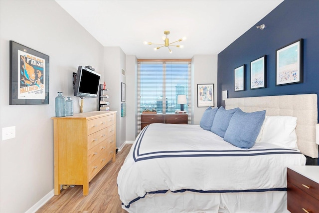 bedroom with baseboards, a chandelier, and light wood-type flooring