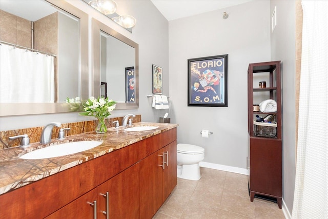 full bathroom with toilet, double vanity, baseboards, and a sink