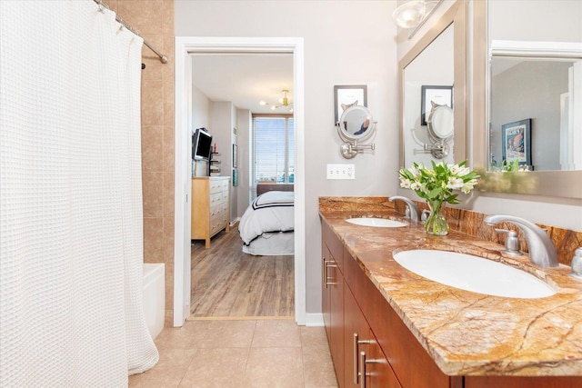 ensuite bathroom with tile patterned flooring, a sink, double vanity, and shower / tub combo