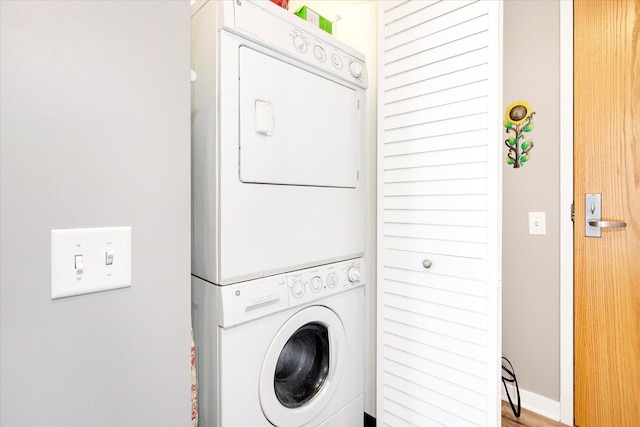 laundry area with baseboards, laundry area, and stacked washer / dryer