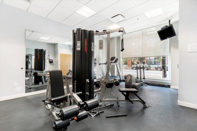 exercise room featuring baseboards and a paneled ceiling